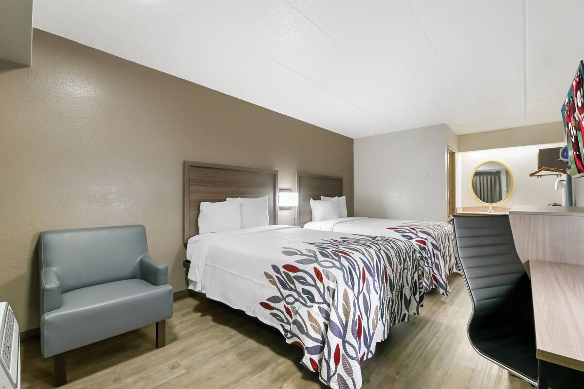 A hotel room with a bed, a desk, a chair, and a sofa.