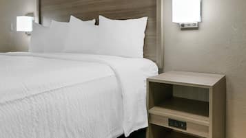A neatly made bed with white bedding, a wooden headboard, and bedside tables with built-in lighting.