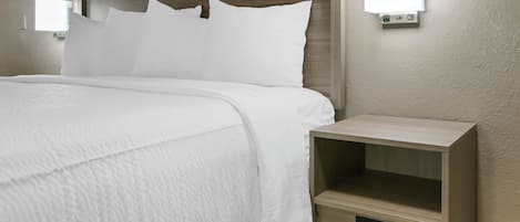 A neatly made bed with white bedding, a wooden headboard, and bedside tables with built-in lighting.