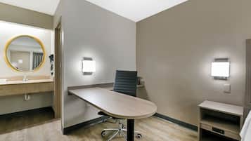 A hotel room with a desk, chair, and a mirror.