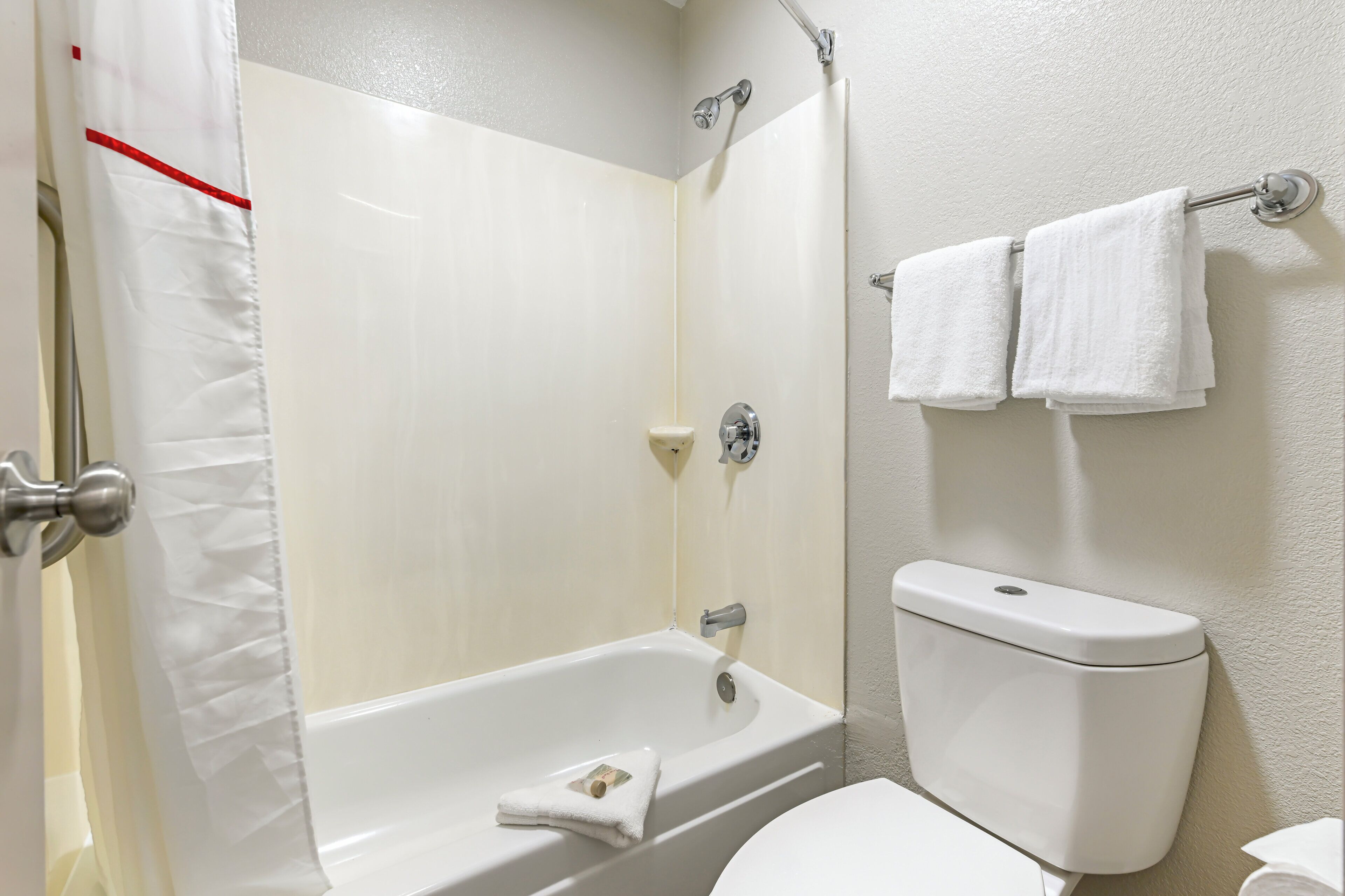 A bathroom with a bathtub, toilet, and a shower curtain.
