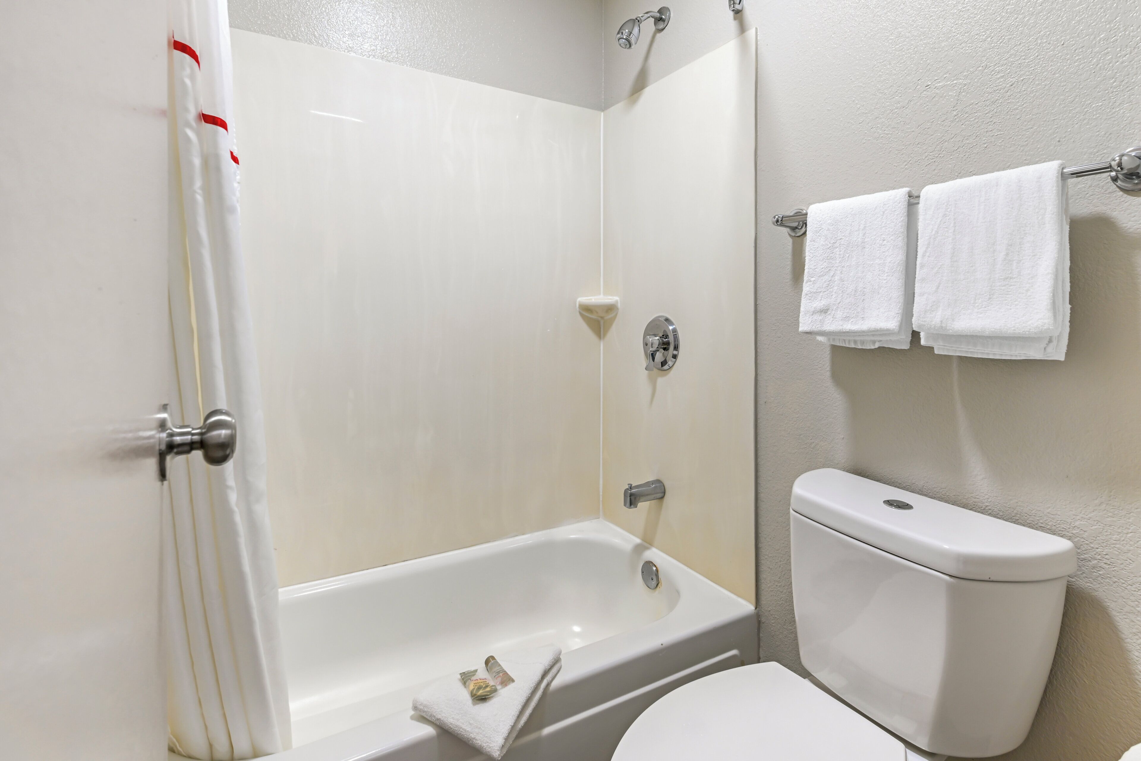 A bathroom with a bathtub, a toilet, and a towel rack with two towels.
