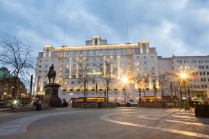 A large, historic building with a statue in front, likely a hotel or public building.