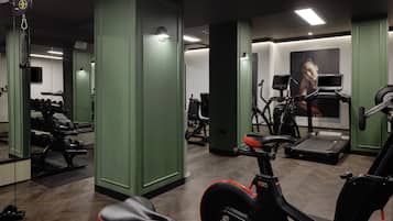 Een sportschool met trainingsapparatuur, spiegels en een loopband.