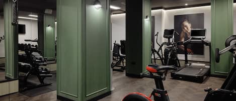 A gym with exercise equipment, mirrors, and a treadmill.