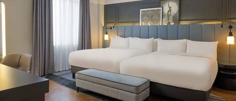 A modern hotel room with a large bed, a desk, and a chair.