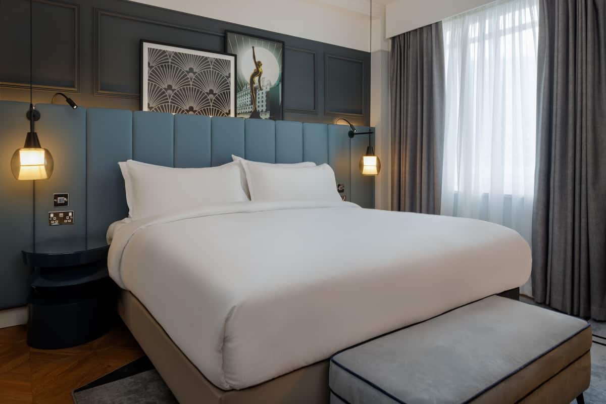Une chambre d’hôtel moderne avec un grand lit, des tables de chevet et des œuvres d’art accrochées au mur.