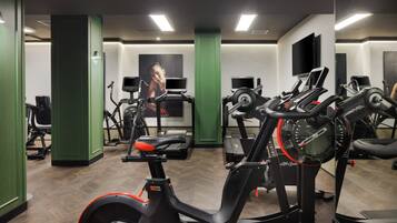 A gym with exercise equipment, green walls, and a large mirror.