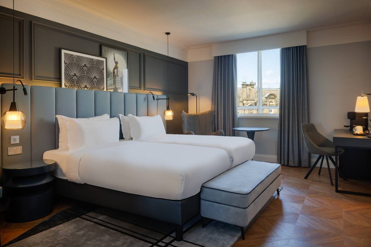 Une chambre d’hôtel avec un grand lit, un bureau, une chaise et une vue sur la ville.