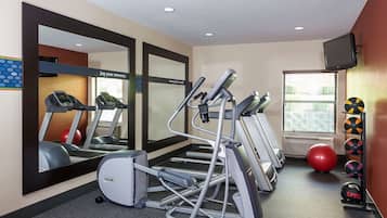Un gimnasio con cintas de correr, elípticas, bicicletas estáticas y una variedad de pelotas de ejercicio.