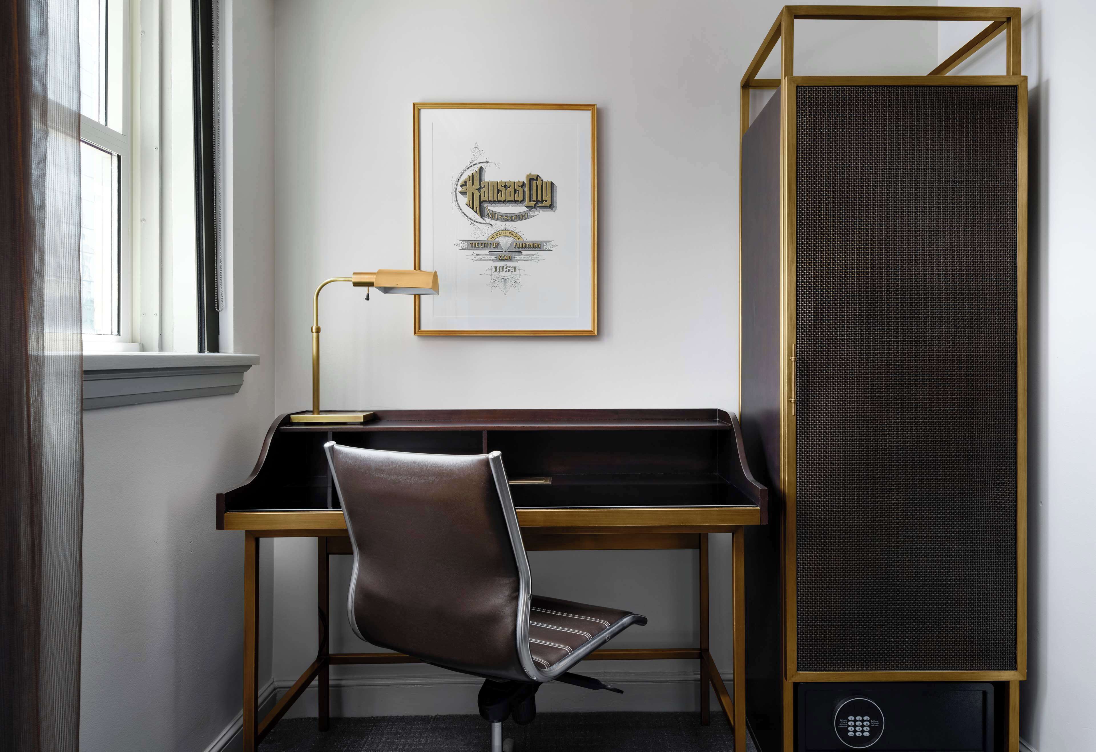Een modern bureau met een lederen stoel, een ingelijste foto aan de muur en een hoge speaker.