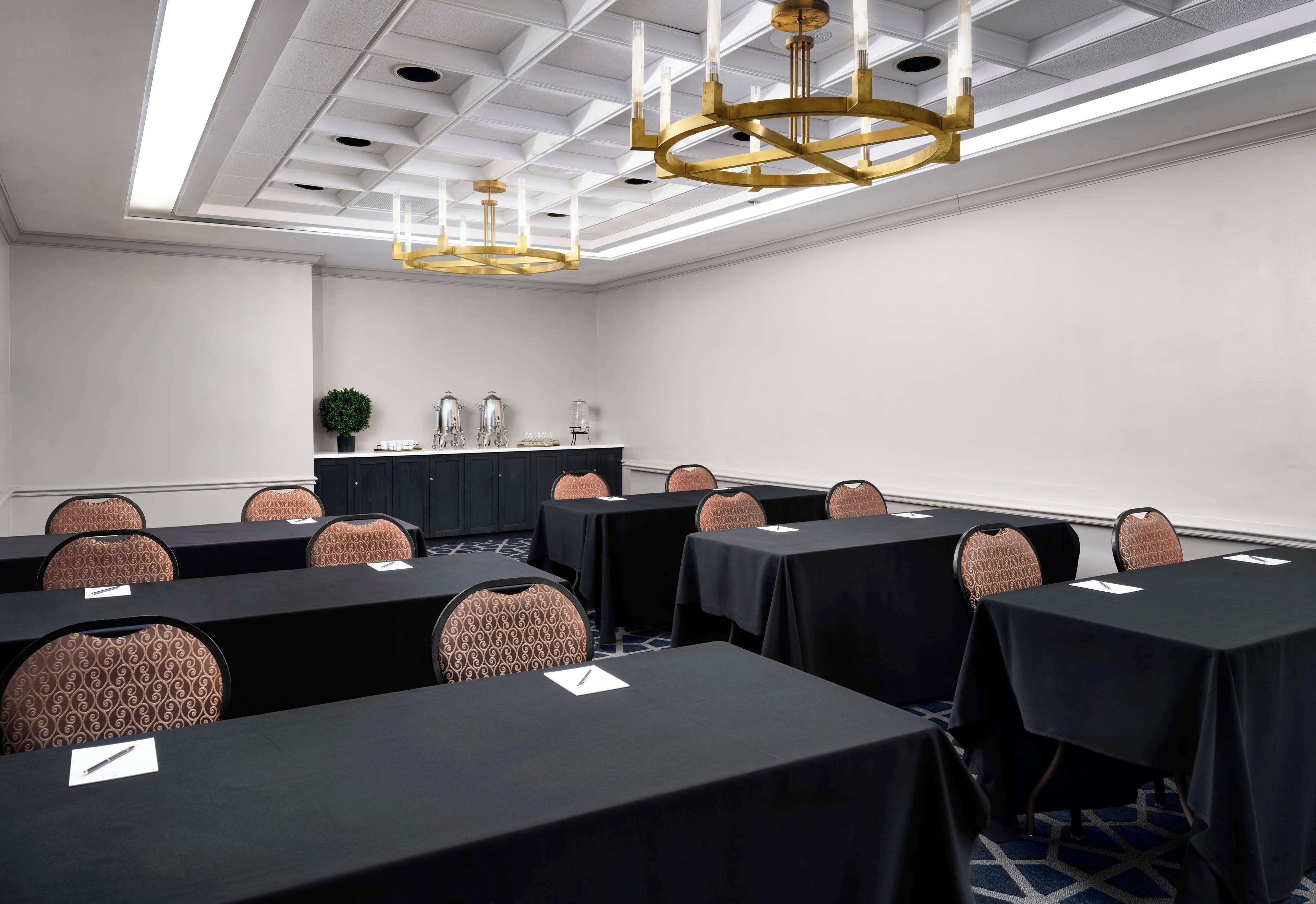 A conference room with tables, chairs, and a podium.