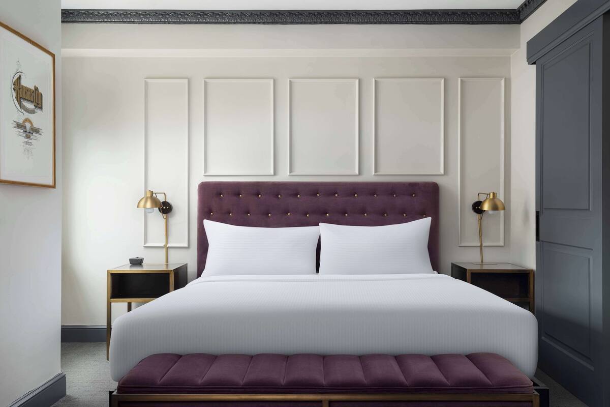 A neatly arranged bedroom with a large bed, two bedside tables, and a bench.