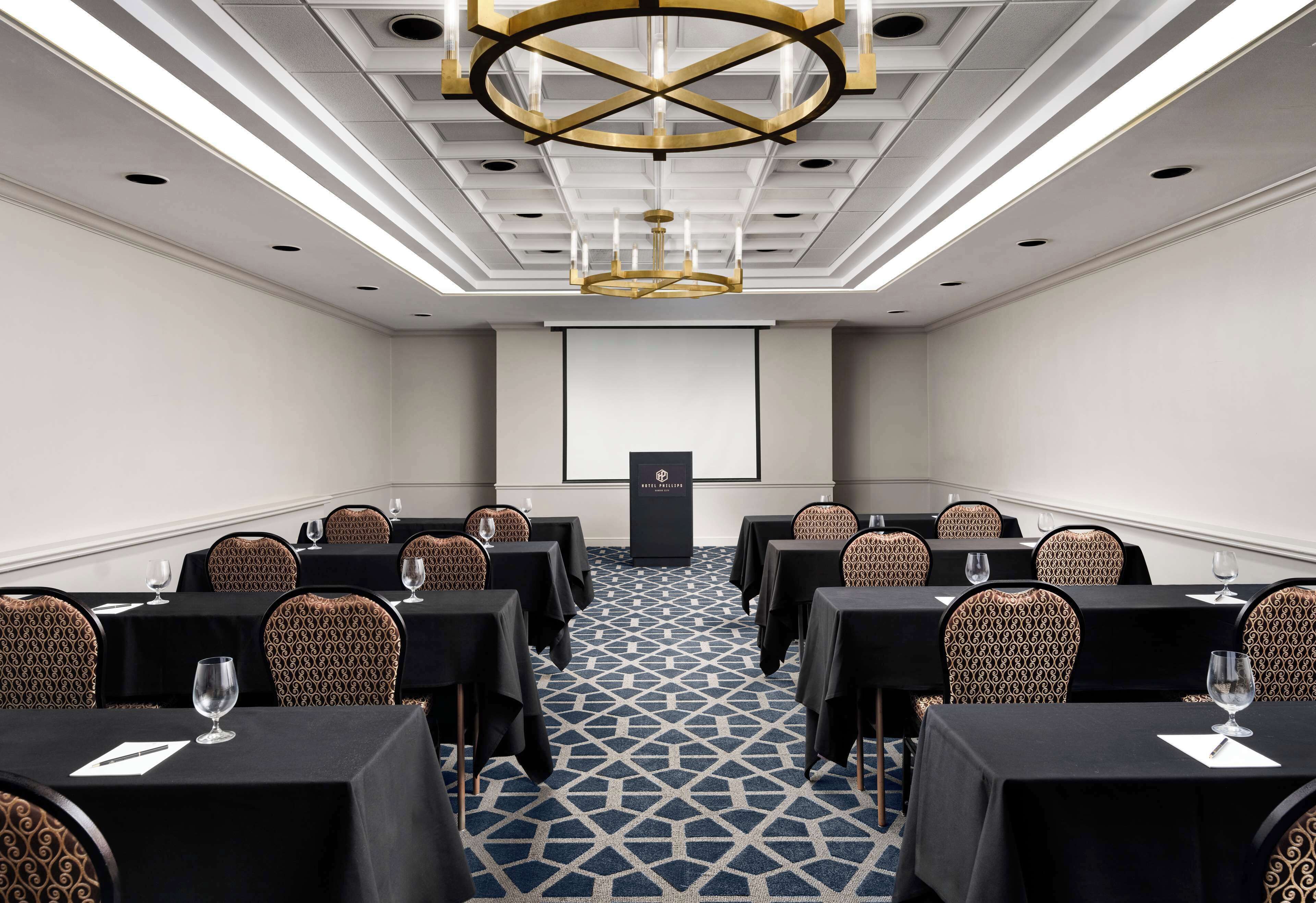 Une salle de conférence dotée d’un tapis à motifs, de tables noires et de chaises à motifs.