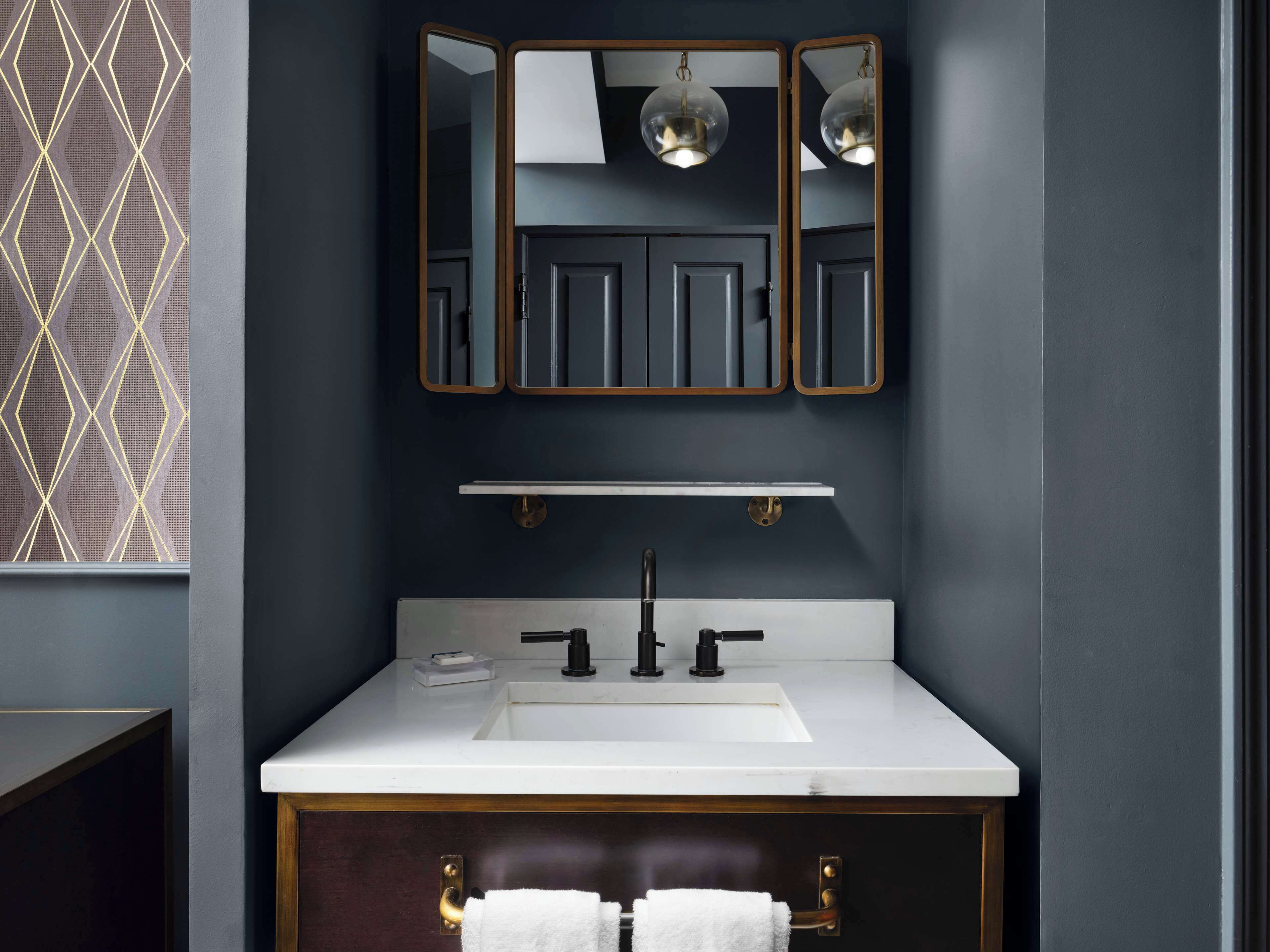 A modern bathroom with a dark gray wall, a white sink, and a mirror above it.