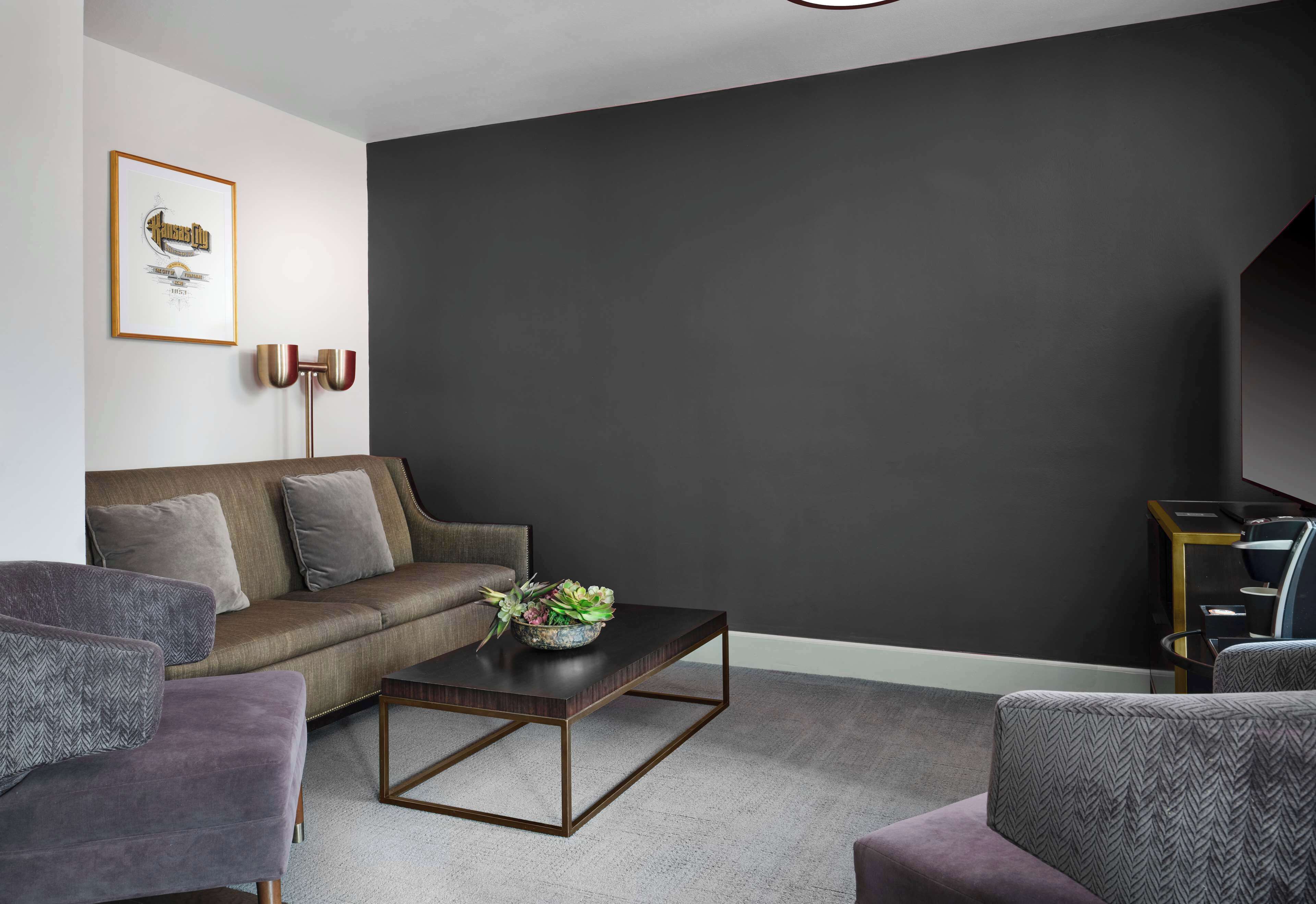 A modern living room with a dark wall, a sofa, a coffee table, and a framed picture on the wall.