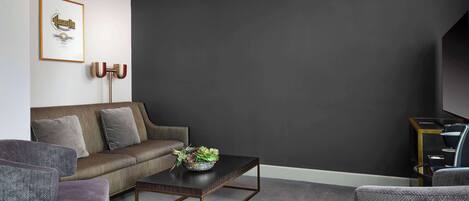 A modern living room with a dark wall, a sofa, a coffee table, and a framed picture on the wall.
