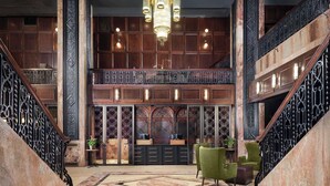 A grand lobby with a high ceiling, ornate chandeliers, and a central staircase.