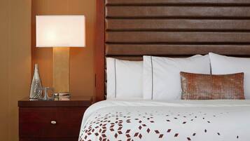 A hotel room with a large bed, a nightstand with a lamp, and a decorative vase.