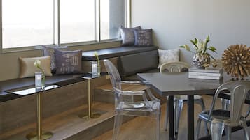 A modern interior with a clear glass dining table, a bench with cushions, and a view of the outdoors through large windows.