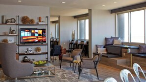 Een moderne woonkamer met een flatscreen televisie, comfortabele zitplaatsen en decoratieve objecten op planken.