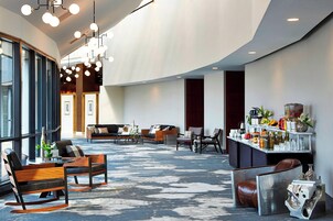 Un'ampia hall dall'arredamento moderno, con diverse zone relax, un bar fornito di numerosi alcolici e un'ampia finestra che offre luce naturale.