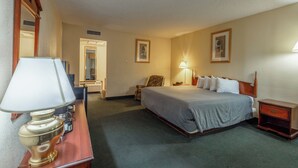 Een hotelkamer met een bed, nachtkastje, lamp, stoel en bureau met lamp.
