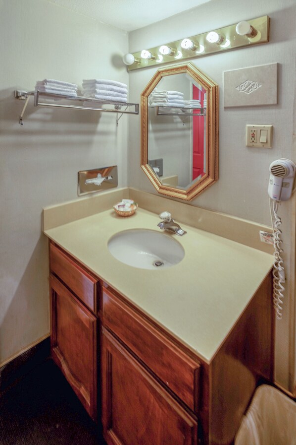 A bathroom with a sink, vanity, mirror, towel rack, and hairdryer. - Royal Holiday Motel By Belvilla Gallup I-40 (Gallup)