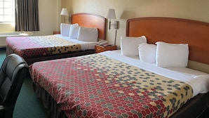 Deux lits doubles avec des couvre-lits à motifs, des lampes de chevet, une table de chevet avec un téléphone et une chaise.