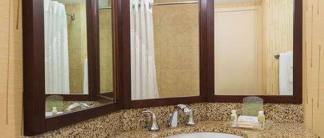 A bathroom with a granite countertop, a white sink, and a large mirror.