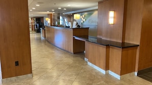 Zona de recepción de hotel con mostrador de madera, suelo de baldosas y una pared con el letrero 'Holiday Inn Express'.