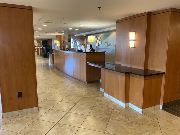 Zona de recepción de hotel con mostrador de madera, suelo de baldosas y una pared con el letrero 'Holiday Inn Express'.