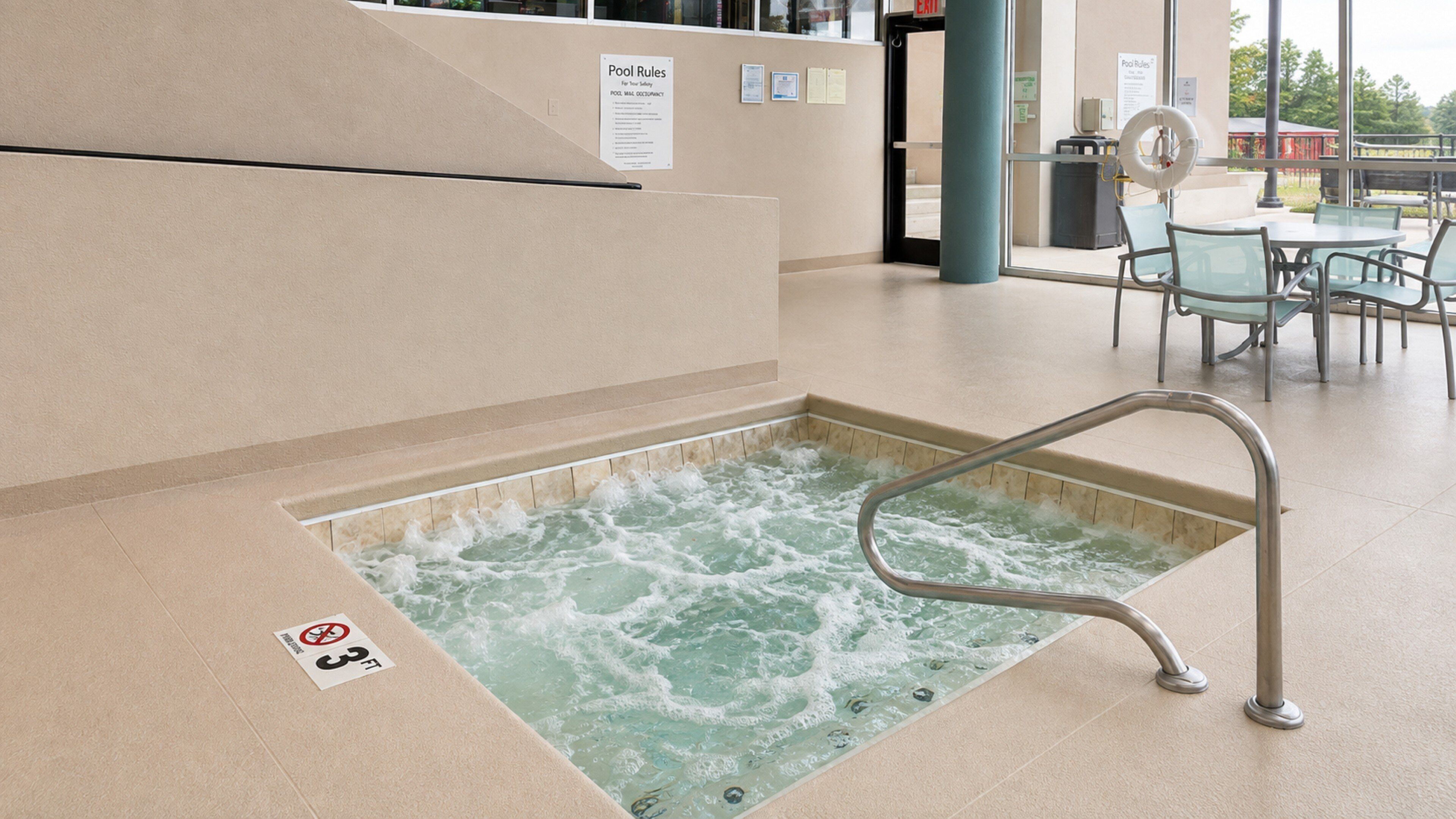 A hot tub area with a safety sign, a pool rules sign, and a no diving sign.