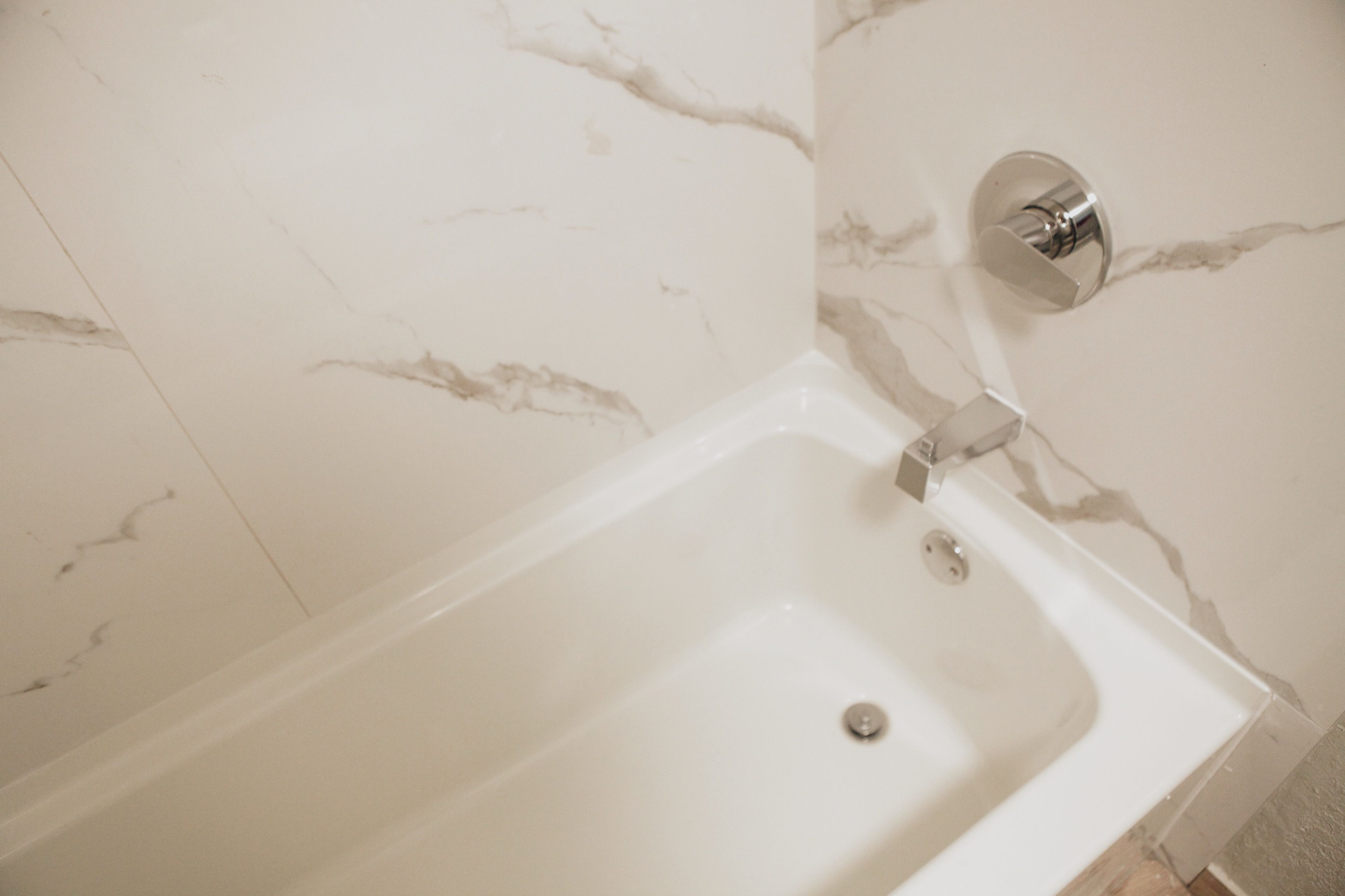 A white bathtub with a chrome faucet and a wall-mounted control.