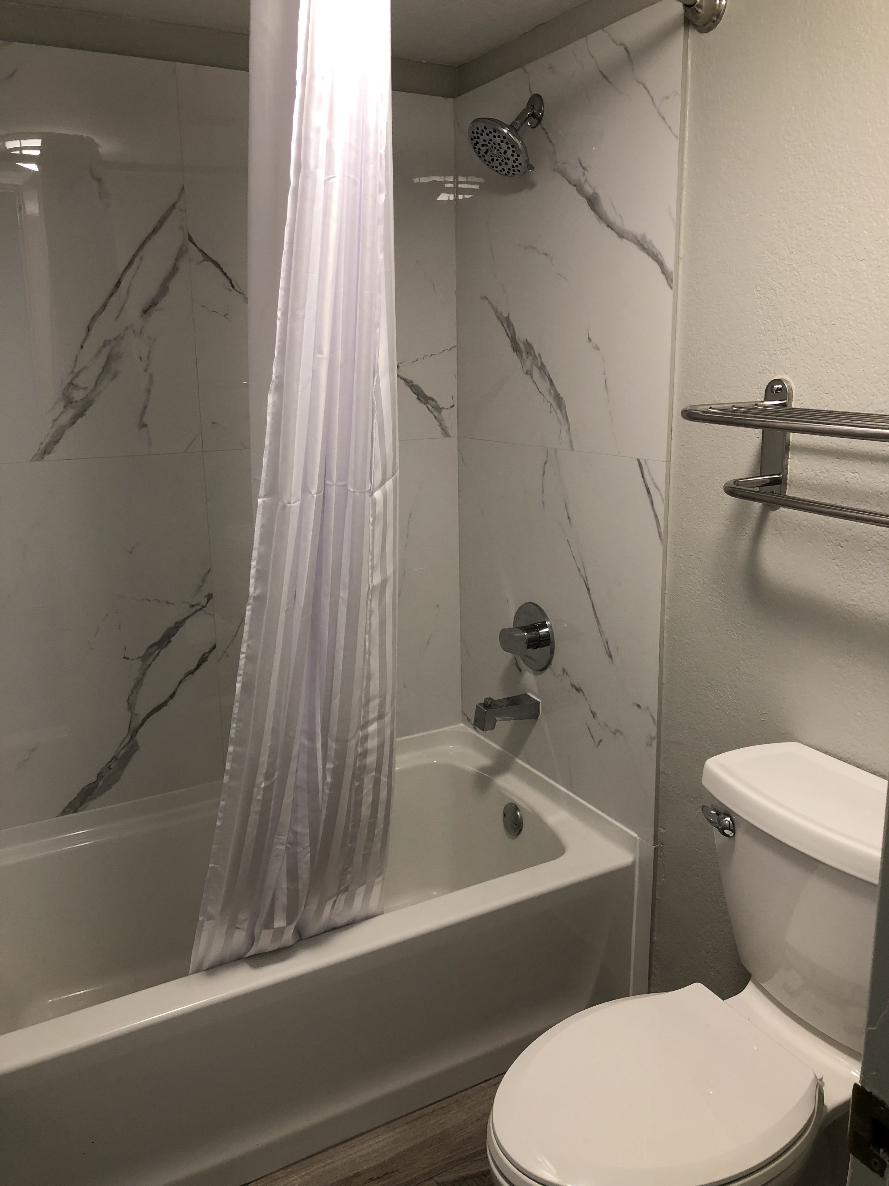 A bathroom with a bathtub, shower, and toilet.