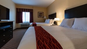 A hotel room with two beds, a TV, a desk, and a window with curtains.