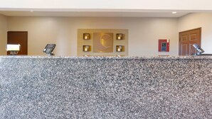A reception desk with a granite countertop, a wall-mounted phone, and a decorative wall piece.