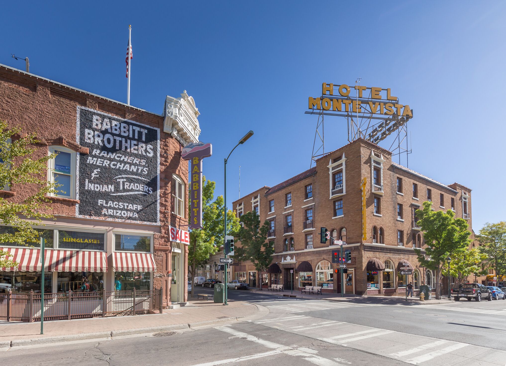 A hotel with a prominent sign, a storefront with a sale sign, and a street intersection.