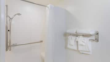 A bathroom with a shower, a towel rack with towels, and a door.