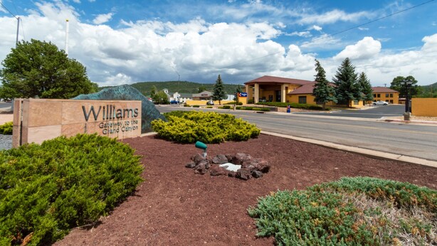 A sign for 'Williams Gateway to the Grand Canyon' with a landscaped area, a road, and buildings in the background. - Comfort Inn Near Grand Canyon (Williams)