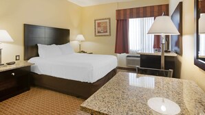 A hotel room with a bed, a desk, a chair, a lamp, a picture on the wall, and a window with curtains. - Comfort Inn Near Grand Canyon (Williams)