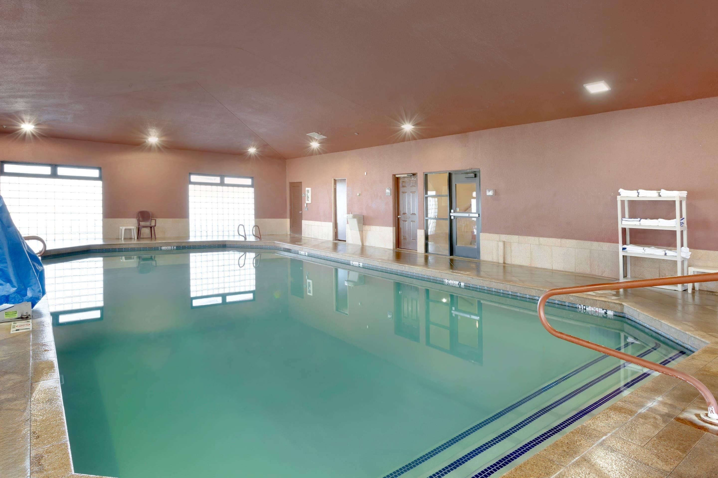 An indoor swimming pool with clear water, a tiled floor, and a blue safety rope.