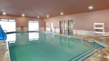Una piscina interior con agua cristalina, piso de baldosas y una cuerda de seguridad azul.