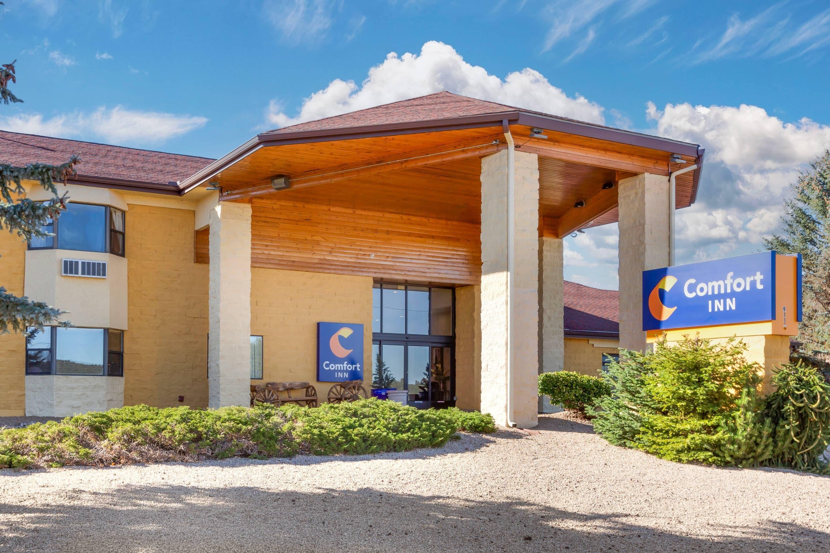 Ein Comfort Inn Hotel mit überdachter Eingangspartei, einem Schotterweg und blauem Himmel.