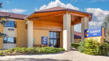 Ein Comfort Inn Hotel mit überdachter Eingangspartei, einem Schotterweg und blauem Himmel.