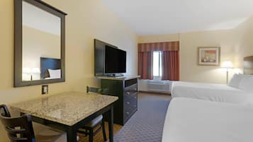 Habitación de hotel con cama, escritorio, silla, televisor y ventana con cortinas.