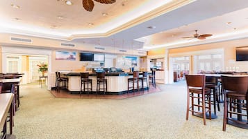 En rymlig hotellobby med en central bardisk, flera sittgrupper och takfläktar.