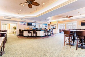 A spacious hotel lobby with a central bar area, multiple seating arrangements, and ceiling fans. - Radisson Resort at the Port (Cape Canaveral)
