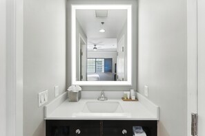 A bathroom with a white sink, a mirror, and a ceiling fan. - Radisson Resort at the Port (Cape Canaveral)