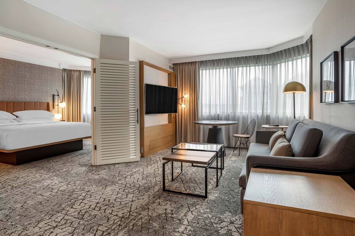 Een hotelkamer met een bed, een slaapbank, een televisie, een klein tafeltje en een stoel.